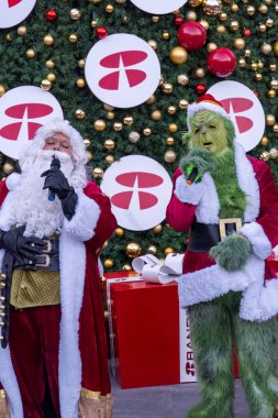 Büyük hediyelerle bir Noel ağacının arkasında şarkı söyleyip dans eden Grinch, Meksika Latin Amerika