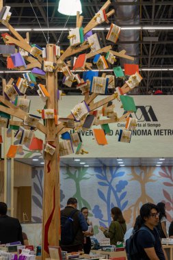 Kitap yeşil yapraklı bir ağaç dalında asılı. Kitaptan görülebilir kır çiçekleri ve Meksika Latin Amerika sayfaları var.