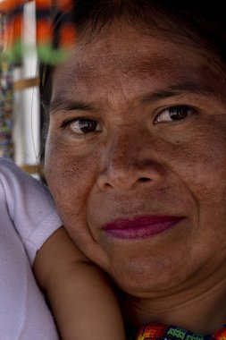 traditional artisan woman carrying her daughter, surrounded by her very colorful chaquira handicraft, in guadalajara mexico, latin american
