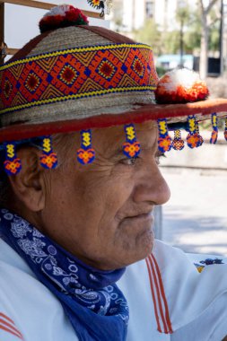 old man of the huichol wixarika culture with his traditional hat, selling his handicraft in mexico guadalajara latin american