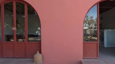 Saksı bitkileri ve ağaçları olan pembe evin dış görünüşü.