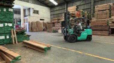 Depoda büyük bir odun yığını olan bir adam çalışıyor. 