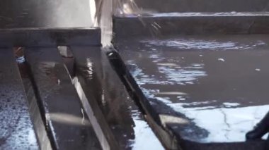 Latin biri atölyenin içindeki çalışma masasında doğal volkanik bir taş tabakasını kesiyor. Kesimi kolaylaştırmak için su, hasarı önlemek için koruma sağlıyor.