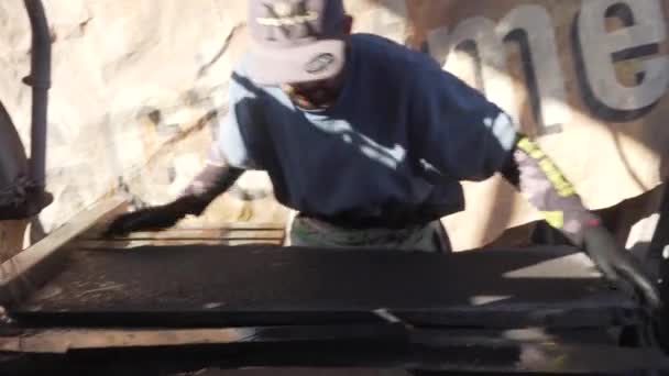 拉丁人在车间内的工作台上切割一块天然火山石板 用水方便切割 保护以避免损坏 — 图库视频影像