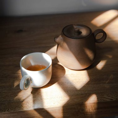 Mor bir gül ağacının üzerinde seramik çaydanlık ile çay fincanları