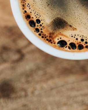 Bir fincan kahve, granit kapakta, sütle süslenmiş, mavi seramik bardakta.