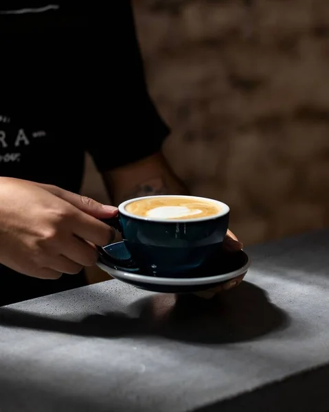cappuccino in ceramic cup on concrete table, young man holding cup of coffee