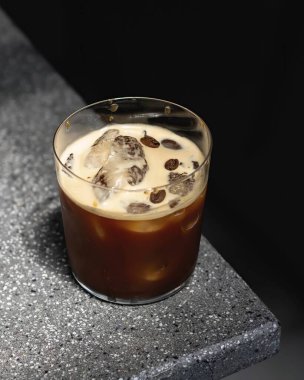 Kahveyi cam bardağa döken latteyi masaya döken havadaki donmuş suyu hareket halindeki beton masa kahvesine döken kahveyi.