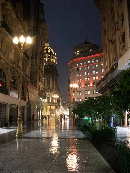 Yağmurlu bir gecede, insanların olmadığı çiçekli bir sokakta.