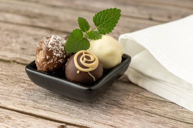 Siyah tabakta trüf mantarı ve kırsal bir ahşap masa üzerinde nane yaprakları.