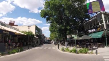 Parçalı bulutlu bir günde, şehrin ana kavşağında, araçlar ve insanların dolaştığı zaman aralığı.