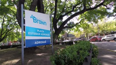 Adrogue şehir meydanında ağaçlar, yeşil alan ve etrafta dolaşan araçların statik görüntüsü.