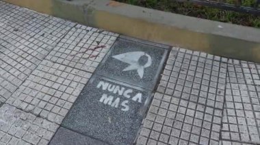 Plaza de Mayo 'nun büyükanneleri ve annelerinin bir daha asla Plaza del Gobierno Meydanı' nda bir fayans üzerine boyanmayacağı ilkesiyle resmedilmiş.