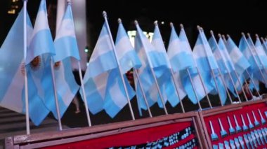 Bir kış gecesinde dikilitaşın önündeki bir sokak tezgahında küçük Arjantin bayraklarını salla