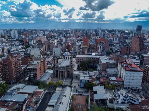 Tucuman şehrinin panoramik hava manzarası, dağlar ve Santo Domingo Katedrali. Kısmen bulutlu bir gökyüzü. Tarih, mimari ve doğayı birleştiren bir manzara. Turizm ve kültür projeleri için ideal.