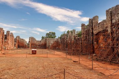 Misiones, Arjantin 'deki San Ignacio Mini harabelerinin sağ kanadından bakın. Çatısız taş duvarlar, eski yapı ve arka plandaki sunak kalıntıları. Kaya zeminleri, kısmen bulutlu gökyüzü ve çevresindeki bitki örtüsü..