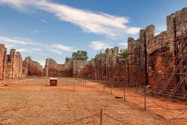 Misiones, Arjantin 'deki San Ignacio Mini harabelerinin sağ kanadından bakın. Çatısız taş duvarlar, eski yapı ve arka plandaki sunak kalıntıları. Kaya zeminleri, kısmen bulutlu gökyüzü ve çevresindeki bitki örtüsü..