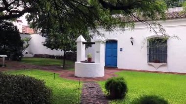Arjantin 'in bağımsızlığının ilan edildiği tarihi Tucuman Evi' ndeki sarnıca doğru derin bir yürüyüş. Yeşil çimenler, çalılar, uçsuz bucaksız dalları olan antik ağaçlar ve mavi kapılı sömürge evleri görülebilir durumda..