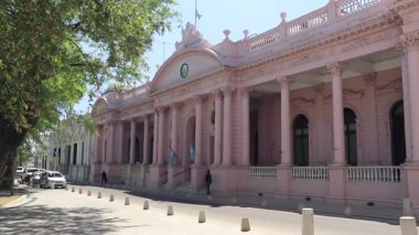 Corrientes Capital 'da sıcak bir gün. Kamera soldan sağa dönüyor. Hükümet Binası, ağaçlar, bitki örtüsü ve Rentas köşesi insanlarla dolu..