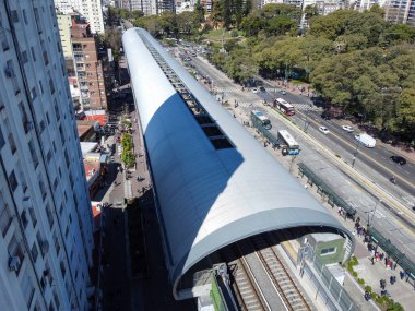 Modern, yükseltilmiş Belgrano C tren istasyonu ve viyadük manzarası şehir manzarasını ve sokak seviyesindeki trafiği yansıtıyor..