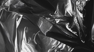 Siyah şeffaf plastik ambalaj dokusu arka planda. Poster tasarımı ve fotoğraf kaplama efekti için gerçekçi plastik. Grafik tasarım kaynakları ve element modellemesi için buruşmuş plastik yüzey deseni.