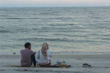 Bir çift aşık sahilde oturmuş okyanusun güzelliğine bakıyor..