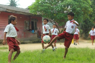 Simalungun Endonezya, 16 Ocak 2024 - Endonezyalı ilkokul öğrencileri okul bahçesinde mutlu bir şekilde futbol oynuyorlar
