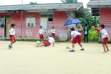 Simalungun Endonezya, 16 Ocak 2024 - Endonezyalı ilkokul öğrencileri okul bahçesinde mutlu bir şekilde futbol oynuyorlar