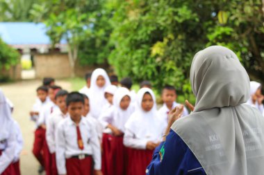 Batu Bara, Endonezya, 26 Ağustos 2024 - Müslüman ilkokul öğrencileri açık havada son sınıf öğrencilerinin açıklamalarını dinliyor