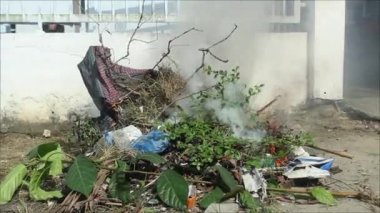 Bahçede ağaç dalları ve plastik atıklar yanıyor.