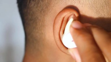 Müzik dinlemek için kablosuz kulaklık takan bir adamın kulağını kapat..