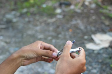 Dışarıda tırnak makası ile tırnak kesen bir gencin elini kapatın.