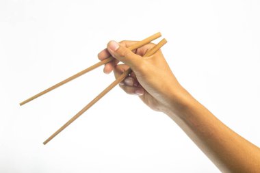 Yemek çubuklarıyla yemeye hazır. Beyaz arka planda bir çift tahta çubuğu tutan bir el.