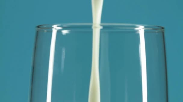 Zbliżenie Mleko Wylewanie Szklanki Szklanki Białe Niebieskie Tło Dla Żywności — Wideo stockowe