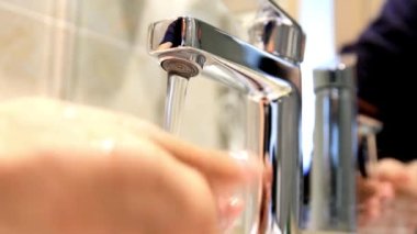 Corona virüsü HD 4k 'yi önlemek için musluklarda sabun ve su ile ellerini yıka.