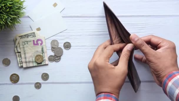 小さな変化がテーブルの上に散らばっている空の財布を持つ男の手 婚約者の債務の背景 — ストック動画