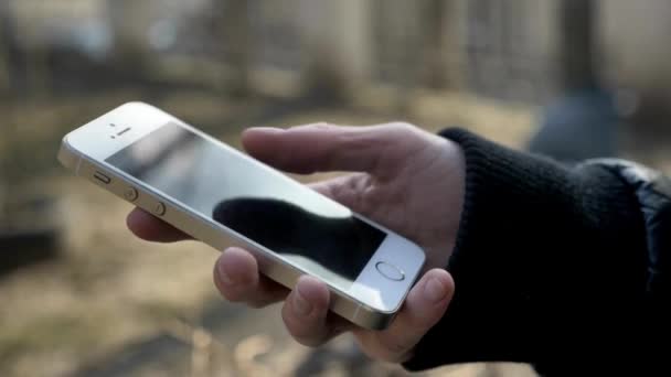 スマートフォンのモバイルアプリを使って携帯電話を持っているクローズアップ屋外の近代的な都市のスマートフォンでスクロール — ストック動画