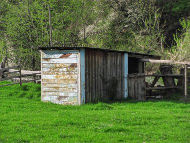 Nehir kenarındaki bir çayırda uzun zamandır terk edilmiş eski, açık ahşap bir ahır var.