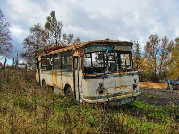 A weathered abandoned bus overgrown with vegetation in Ukraine