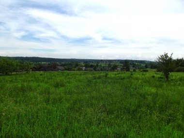 Önünde saman çayırları ve aşağısında bir köy olan huzurlu bir kırsal alan.