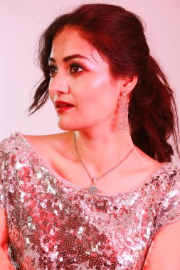 Çekici, şık, gümüş bluzlu ve kolyeli model, neon ışıklı stüdyoda poz veren küpeler.. 