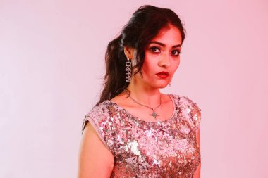 Çekici, şık, gümüş bluzlu ve kolyeli model, neon ışıklı stüdyoda poz veren küpeler.. 