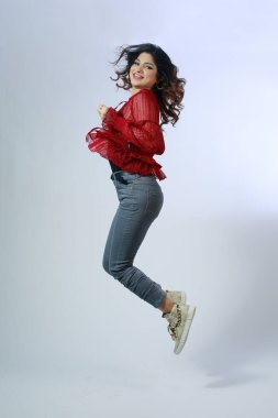 Mutluluk, özgürlük, hareket ve insanlar konsepti - gülümseyen genç kadın beyaz arka planda havaya atlıyor