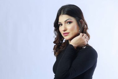 Beyaz arka planda uzun kollu siyah kazaklı bir kız.