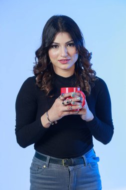 Siyah eşofmanlı genç ve güçlü bir kadın kırmızı bardaktan sıcak içeceği yudumluyor. İzole edilmiş portre