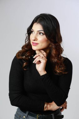 Beyaz arka planda uzun kollu siyah kazaklı bir kız.