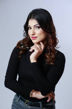 Beyaz arka planda uzun kollu siyah kazaklı bir kız.