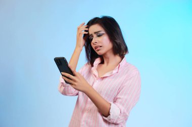 Akıllı telefonu kullanarak mesaj atan genç ve güzel bir kadın. Kafa kafaya verip strese girmiş. Utanç ve şaşkınlık dolu bir yüz ifadesi. Hata için korku ve üzüntü.