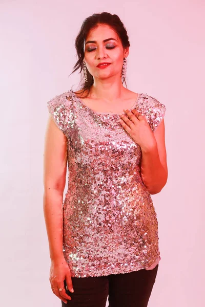 Çekici, şık, gümüş bluzlu ve kolyeli model, neon ışıklı stüdyoda poz veren küpeler.. 