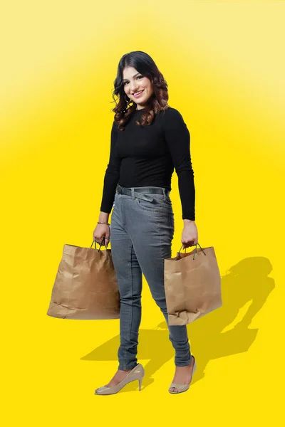 Cheerful happy woman enjoying shopping, she is carrying shopping bags isolated on a studio background.